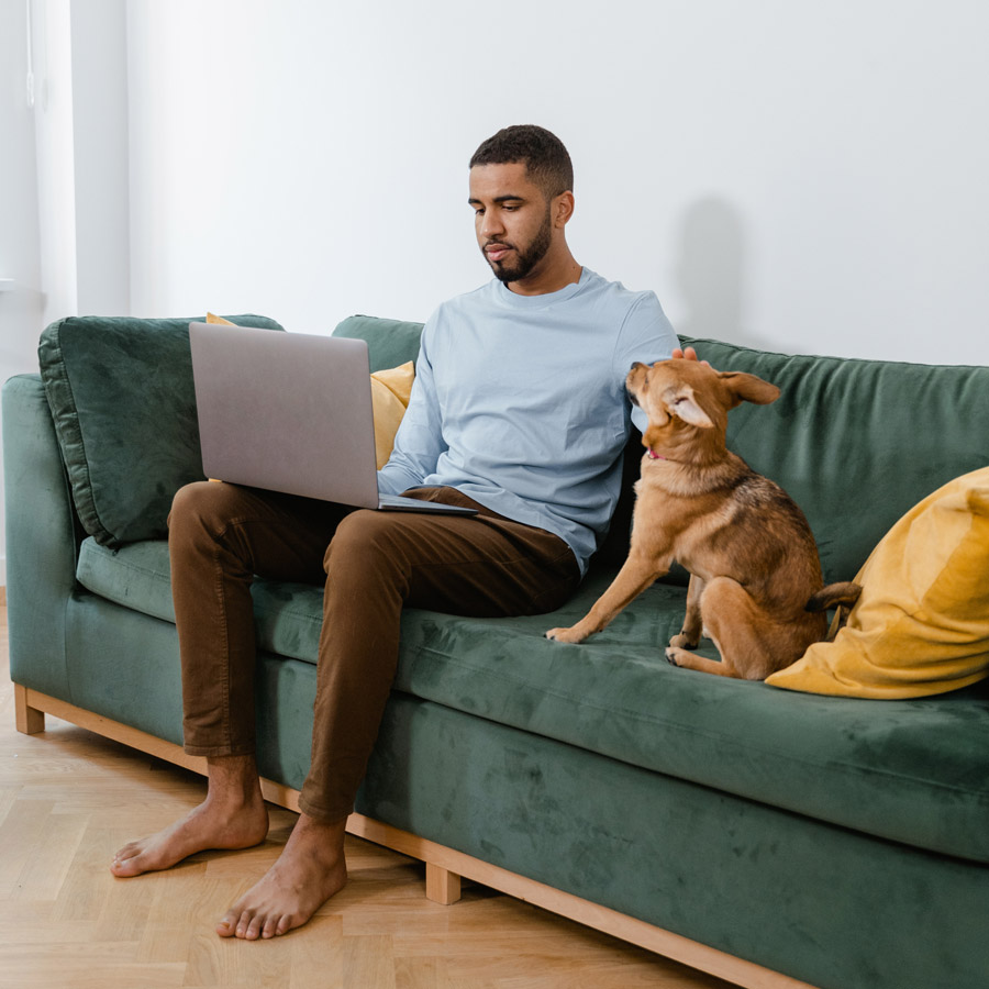 persona con perro y ordenador en sofa  - solicitar nacionalidad española por internet - certificadoelectroni
