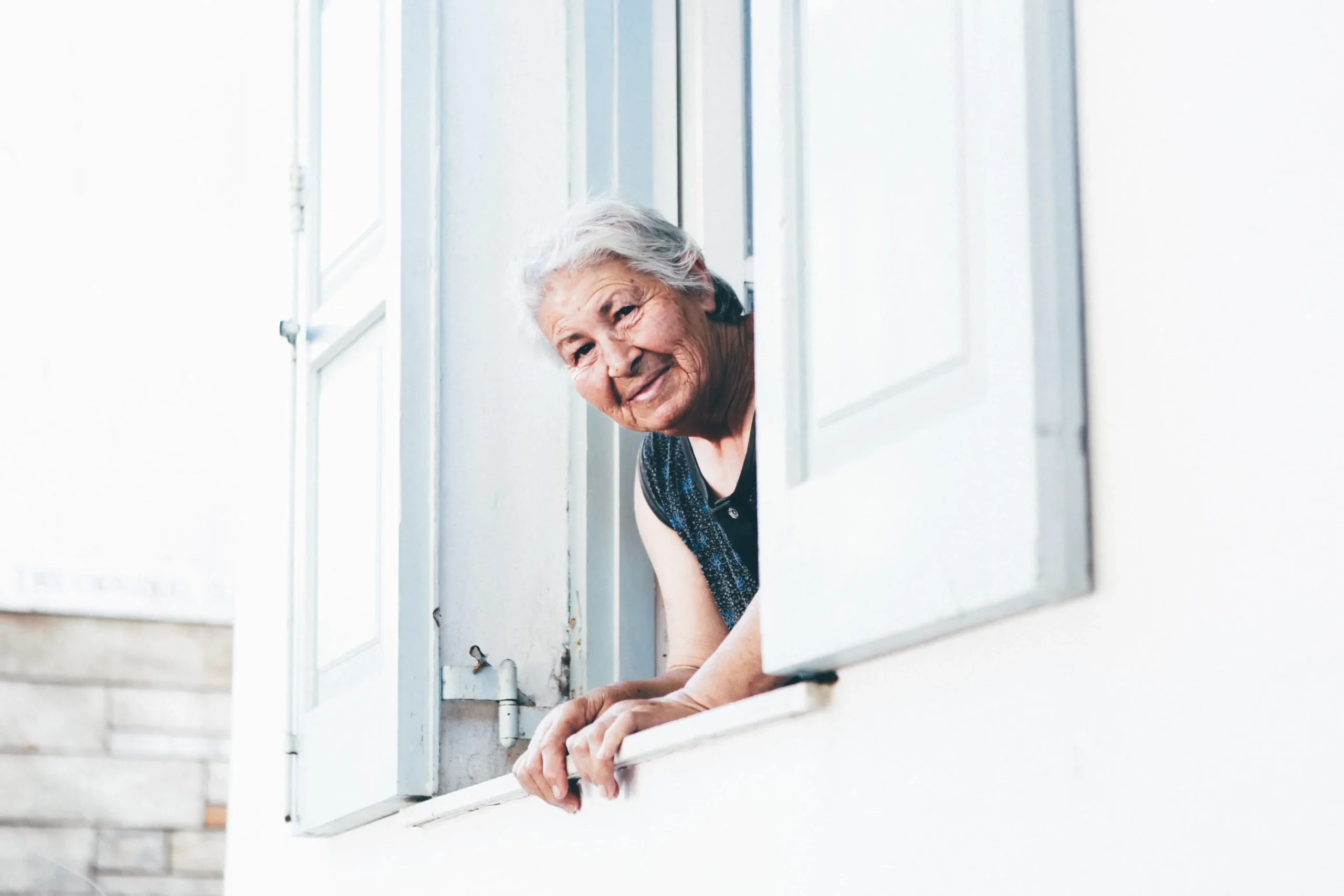Anciana asomada a una ventana - Complemento para reducir la brecha de género en las pensiones - CertificadoElectronico.es